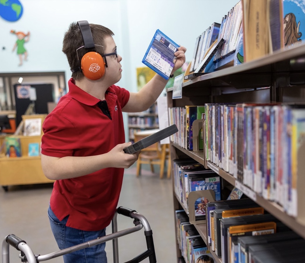 Person looking at Blu Ray disc in a library aisle